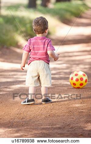 Toddler boy with ball on dirt road View Large Photo Image Stock Photo - Toddler boy with ball on dirt road. Fotosearch