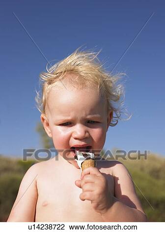 Stock Image - Toddler girl eating ice cream cone. Fotosearch