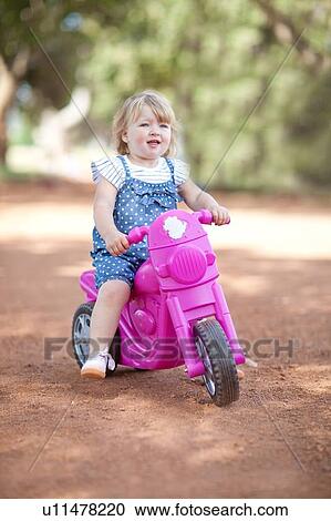 Toddler girl riding toy on dirt road View Large Photo Image Stock Image - Toddler girl riding toy on dirt road. Fotosearch