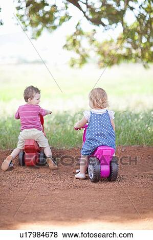 Stock Photo - Toddlers riding toys on dirt road. Fotosearch