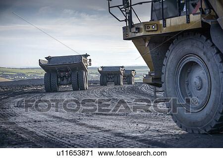 Stock Image - Trucks with coal rocks at surface mine. Fotosearch