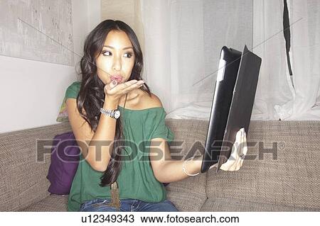 Woman blowing kiss at tablet computer View Large Photo Image Stock Image - Woman blowing kiss at tablet computer. Fotosearch
