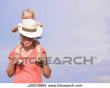 Picture - Woman carrying daughter on shoulders. Fotosearch