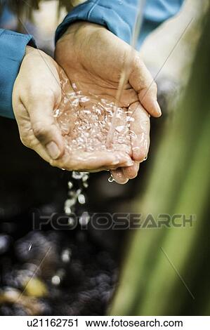 Stock Image - Woman catching water stream in hands. Fotosearch