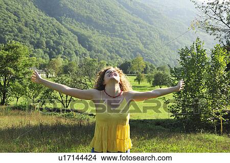 Picture - Woman cheering in grassy field. Fotosearch