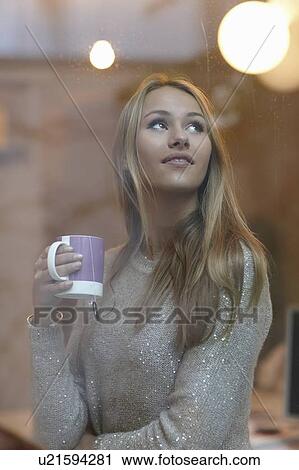 Stock Image - Woman drinking coffee behind window. Fotosearch