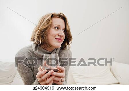 Stock Photo - Woman drinking wine on sofa. Fotosearch