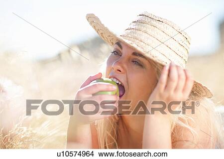 Woman eating apple in tall grass View Large Photo Image Picture - Woman eating apple in tall grass. Fotosearch