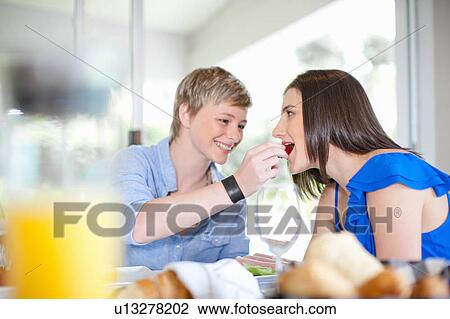 Stock Image - Woman feeding girlfriend breakfast. Fotosearch