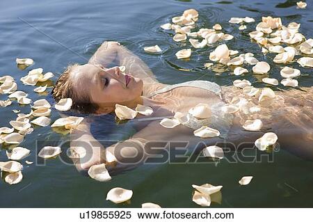Stock Photography - Woman floating in petals in still lake. Fotosearch