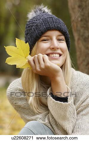 Stock Image - Woman holding autumn leaf outdoors. Fotosearch