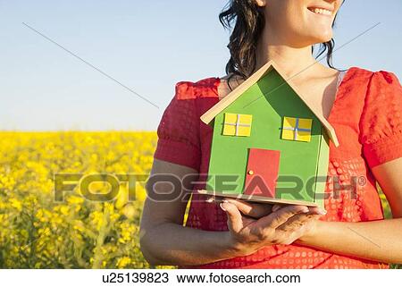 Woman holding model house in field View Large Photo Image Stock Image - Woman holding model house in field. Fotosearch