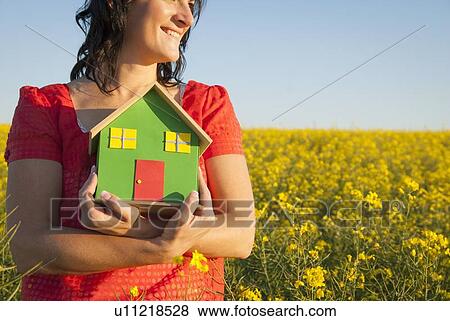 Woman holding model house in field View Large Photo Image Stock Photo - Woman holding model house in field. Fotosearch