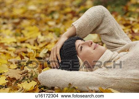 Woman laying in autumn leaves outdoors View Large Photo Image Picture - Woman laying in autumn leaves outdoors. Fotosearch