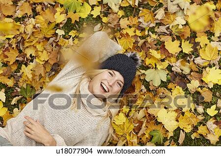 Woman laying in autumn leaves outdoors View Large Photo Image Picture - Woman laying in autumn leaves outdoors. Fotosearch