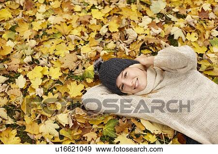 Woman laying in autumn leaves outdoors View Large Photo Image Stock Photo - Woman laying in autumn leaves outdoors. Fotosearch