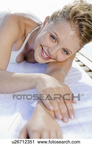 Stock Image - Woman laying on towel outdoors. Fotosearch