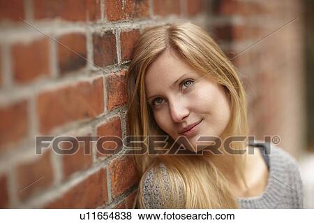 Stock Photo - Woman leaning against brick wall. Fotosearch