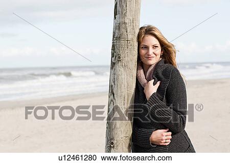 Woman leaning on pole on beach View Large Photo Image Stock Image - Woman leaning on pole on beach. Fotosearch