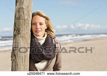 Woman leaning on pole on beach View Large Photo Image Stock Image - Woman leaning on pole on beach. Fotosearch