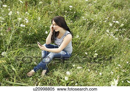 Woman listening to headphones in grass View Large Photo Image Stock Photography - Woman listening to headphones in grass. Fotosearch