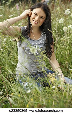 Woman listening to headphones in grass View Large Photo Image Stock Photography - Woman listening to headphones in grass. Fotosearch