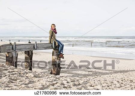 Stock Photograph - Woman on abandoned pier on beach. Fotosearch