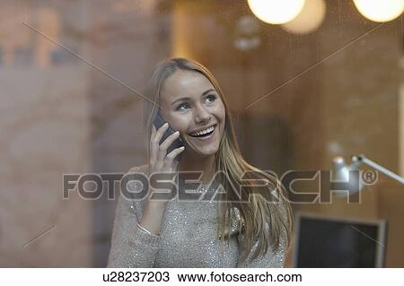 Stock Image - Woman on cell phone behind window. Fotosearch