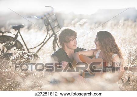 Stock Image - Woman playing guitar for boyfriend. Fotosearch
