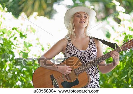 Picture - Woman playing guitar outdoors. Fotosearch