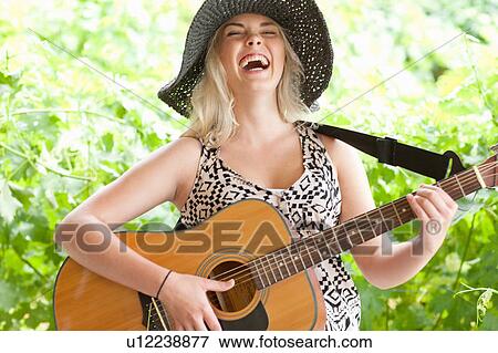 Stock Photo - Woman playing guitar outdoors. Fotosearch