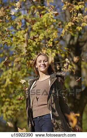 Stock Image - Woman playing in autumn leaves. Fotosearch