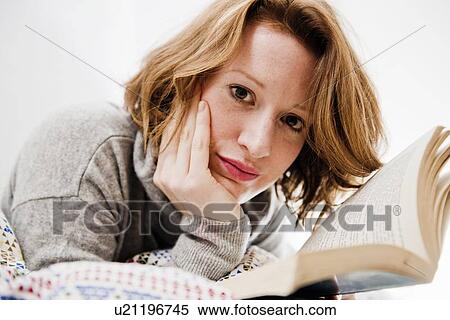 Stock Photography - Woman reading book on bed. Fotosearch