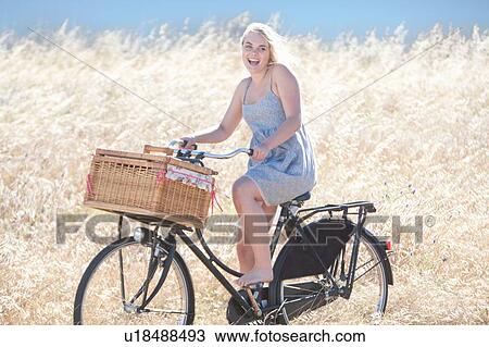 Woman riding bicycle in tall grass View Large Photo Image Stock Image - Woman riding bicycle in tall grass. Fotosearch