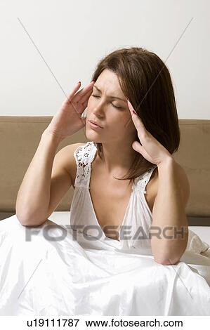 Woman rubbing temples in bed View Large Photo Image Stock Photo - Woman rubbing temples in bed. Fotosearch