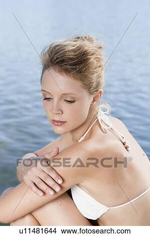 Picture - Woman sitting by still lake. Fotosearch