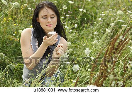 Stock Image - Woman sitting in tall grass. Fotosearch
