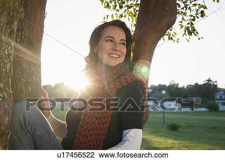 Woman sitting in tree in park View Large Photo Image Stock Image - Woman sitting in tree in park. Fotosearch