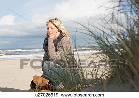 Stock Photo - Woman sitting on beach. Fotosearch