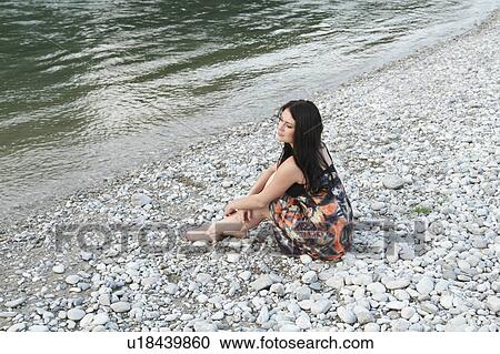 Woman sitting on rocky beach View Large Photo Image Stock Image - Woman sitting on rocky beach. Fotosearch