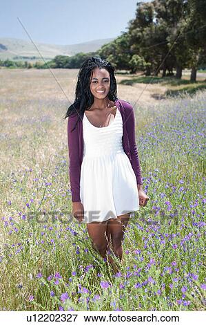 Stock Photo - Woman standing in field of flowers. Fotosearch