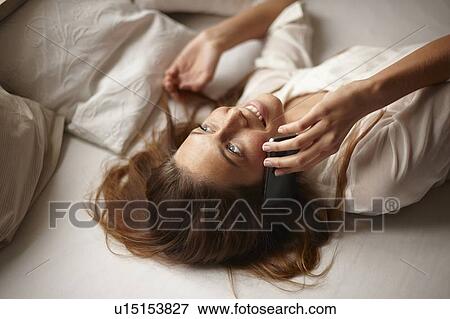 Woman talking on cell phone in bed View Large Photo Image Stock Photo - Woman talking on cell phone in bed. Fotosearch