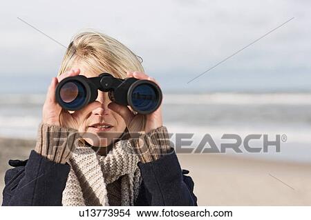 Woman using binoculars on beach View Large Photo Image Picture - Woman using binoculars on beach. Fotosearch