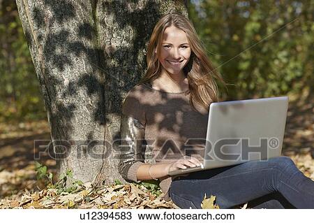 Woman using laptop in autumn leaves View Large Photo Image Stock Image - Woman using laptop in autumn leaves. Fotosearch