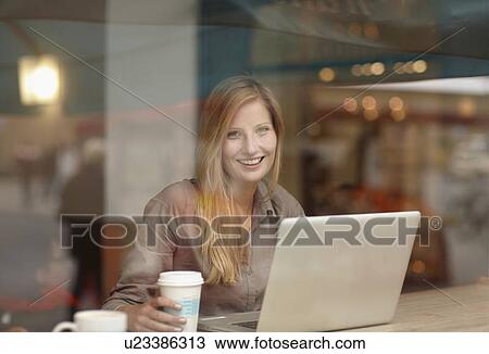 Stock Image - Woman using laptop in coffee shop. Fotosearch
