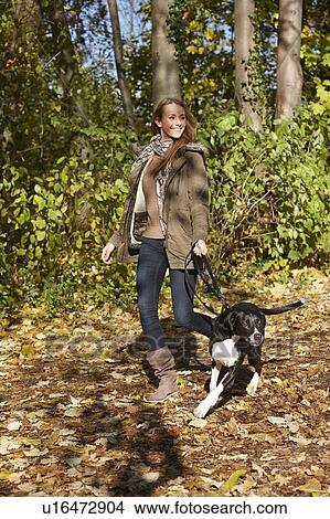 Picture - Woman walking dog in forest. Fotosearch