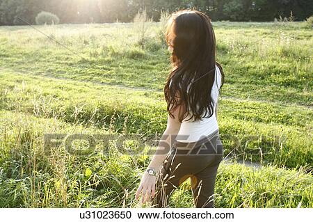 Stock Image - Woman walking in rural field. Fotosearch