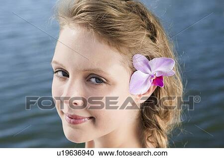 Stock Image - Woman wearing flower in her hair. Fotosearch