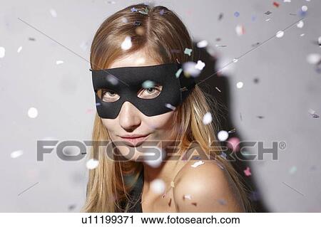 Stock Image - Woman wearing mask in confetti. Fotosearch