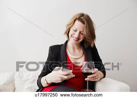 Woman with wine using cell phone View Large Photo Image Stock Image - Woman with wine using cell phone. Fotosearch